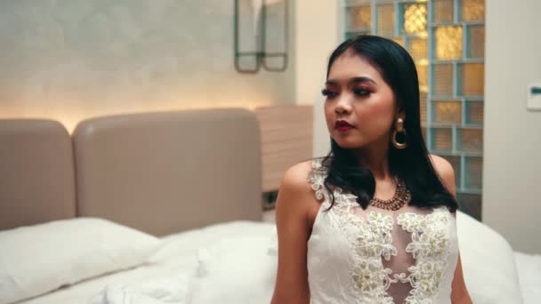 Uma Mulher Asiática Vestido Branco Senta Uma Cama Olha Sarcasticamente — Vídeo de Stock