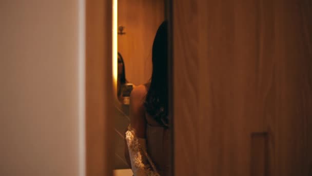 一名亚洲妇女正在一家宾馆房间的浴室镜子前脱衣服 — 图库视频影像