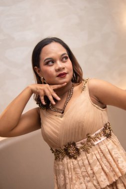 Asyalı bir kadın güzel poz veriyor makyajlı ve gece otelde zarif bir parti elbisesi giyiyor.