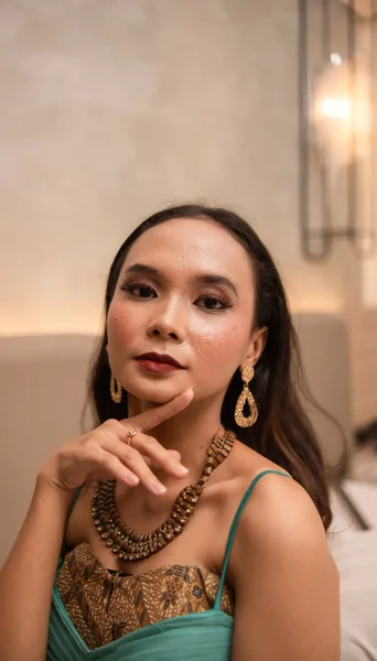 金のネックレスとイヤリングを持つアジアの女性は 夜の夕食の前にホテルの部屋で美しくポーズしています — ストック写真