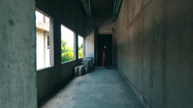 Asyalı bir adam gün boyunca ürkütücü görünen bir binanın arka sokağında duruyor.