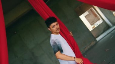 Asyalı bir adam gün boyunca kırmızı bir iple oynuyor ve asılıyor.
