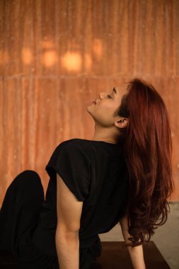 Kahverengi bir masada uyuyan Asyalı bir adam. Gün boyunca uzun saçları sarkmış.