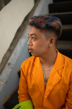 Sarı takım elbiseli Asyalı bir adam gündüz vakti bozuk bir asansörde duruyor.