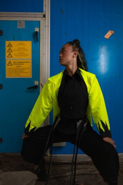 Egzotik bir teni olan Asyalı bir adam sabah mavi bir arka planın önünde çömeliyor.