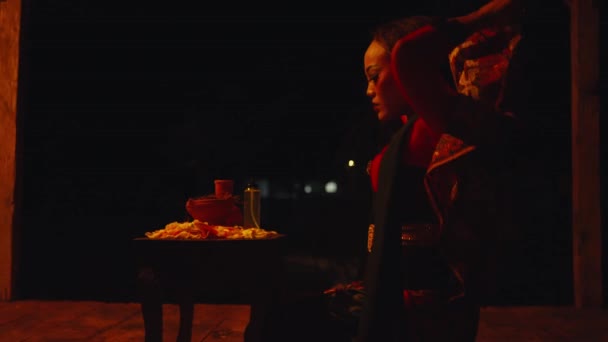 女性は夜に怖い小屋で儀式のテーブルから口紅を取っています — ストック動画