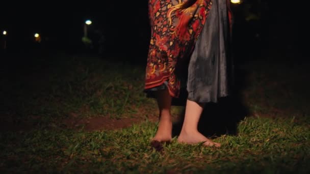 一位亚洲女人的腿在绿色的草地上柔韧地跳舞 晚上穿着蜡染的裙子 — 图库视频影像