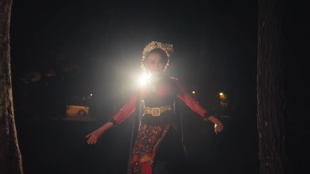 アジアの女性が夜に金のアクセサリーで彼女の黒い髪の束を身に着けながらライトの前で踊っている間歩きます — ストック動画