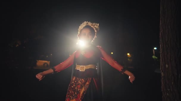 一位亚洲女人一边在灯光前跳舞一边走路 晚上还戴着一个饰有金色饰物的黑色发髻 — 图库视频影像