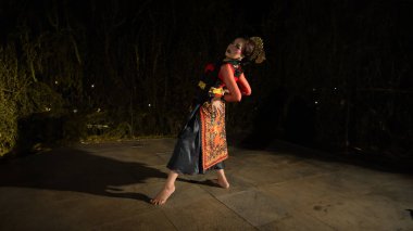 Sahne ışıklarının altında parlayan mücevher takan Endonezyalı bir dansçı o geceki gösterinin parlaklığını artırır.