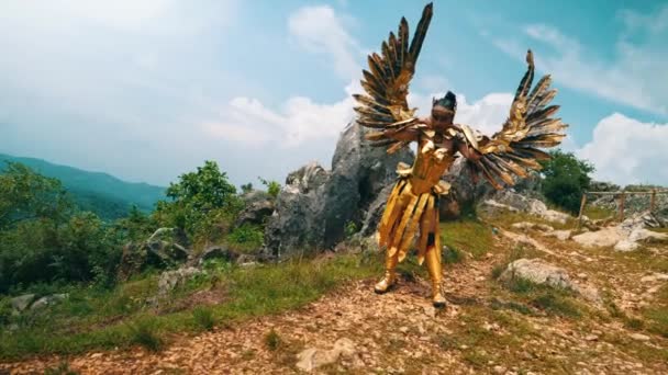 Female Warrior Golden Costume Wings Standing Rocky Mountain Blue Sky — Stock Video