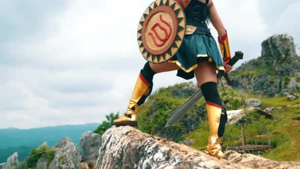 日中の崖の上に 剣と黄金の盾を持った女性の戦士が — ストック動画
