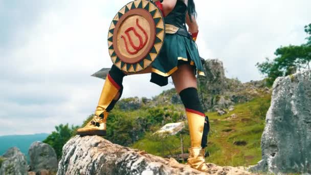 一个拿着剑和金盾勇敢地站在悬崖上的女战士 — 图库视频影像