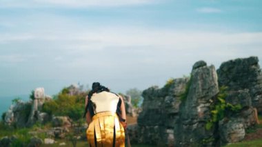 Dişi bir savaşçı lider dağın zirvesinde mağlup olur ve iki yoldaşı onu destekleyen elleriyle teselli etmeye gelir..