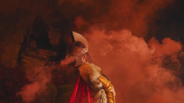男性の兵士は夜に王宮の劇的で激しい赤い煙の周りに鋭い目とタフな鎧で立っています — ストック動画