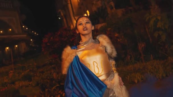 金の鎧の女性兵士は 夜に王宮の前に立っているときに強い肩と豪華さを示しています — ストック動画