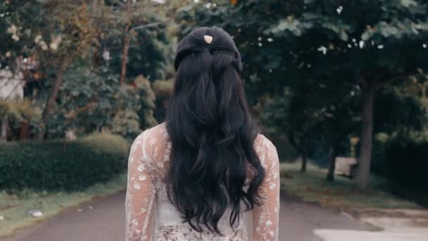 公園内を歩く長髪の女性のリアビュー 昼間の孤独と熟考を象徴する — ストック動画