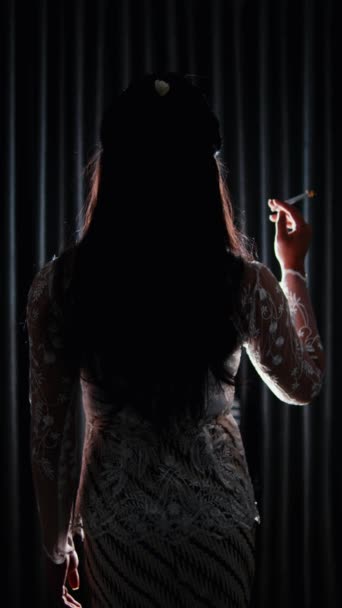 Silhouet Van Een Vrouw Die Rookt Tegen Een Donker Gordijn — Stockvideo