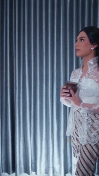 穿着花边衣服的优雅女人拿着一杯饮料 若有所思地望着窗帘背景 — 图库视频影像