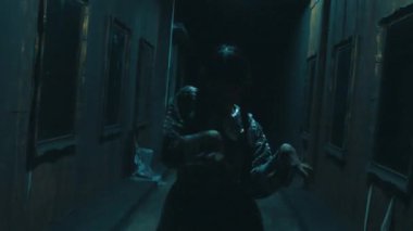 Duvarlarında resimlerle loş bir koridorda dans eden gizemli bir figür perili evin içinde şüphe ve entrika uyandırıyor.