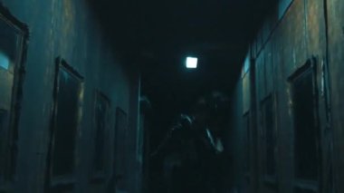 Duvarlarında resimlerle loş bir koridorda dans eden gizemli bir figür perili evin içinde şüphe ve entrika uyandırıyor.