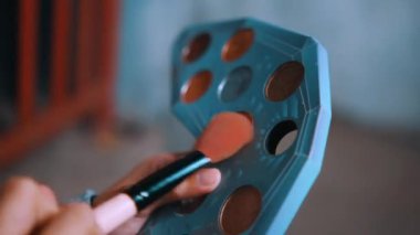 Perili evin içinde seçici bir odak ve bulanık bir arka plan ile el ele tutuşan bir makyaj fırçası.