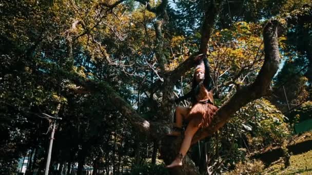 Persona Traje Tribal Posando Árbol Exuberante Bosque Durante Día — Vídeos de Stock