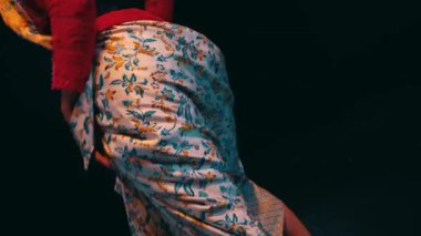 a traditional Javanese dancer dancing and wiggling her butt while performing on stage at night.