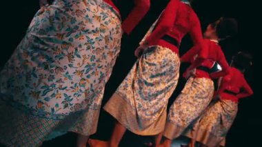a traditional Javanese dancer dancing and wiggling her butt while performing on stage at night.