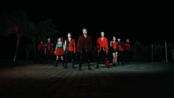 夜のダンサーのグループは 劇的な照明と活気に満ちた赤い衣装で 夜間にエネルギーと動きを示しています — ストック動画