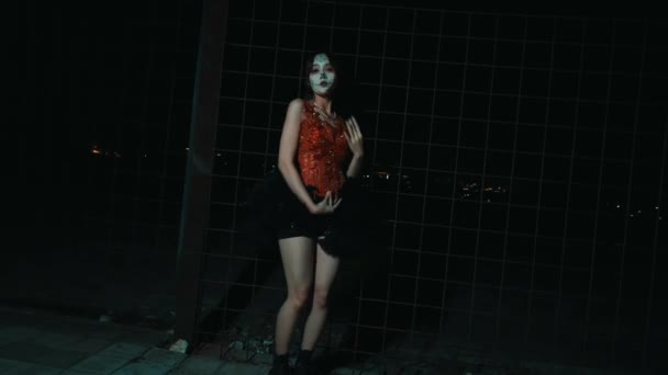身着面具和服装的人晚上靠在金属格栅上 在夜里营造出一种神秘而富有戏剧性的气氛 — 图库视频影像