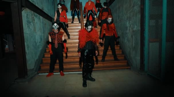 Grupo Pessoas Trajes Vermelhos Pretos Com Máscaras Dançando Uma Escada — Vídeo de Stock
