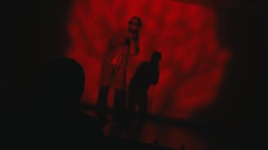 Şarkıcı gece boyunca kırmızı spot ışıkları ve gölge siluetiyle sahnede performans sergiliyor