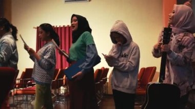 Bir toplantı ya da etkinlik sırasında sırada bekleyen çeşitli kadın grupları, bazıları gece boyunca kitap ve gitar tutuyor.