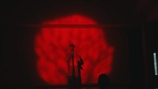 극적인 빨간색 조명과 추상적인 무대에 가수의 실루엣 — 비디오