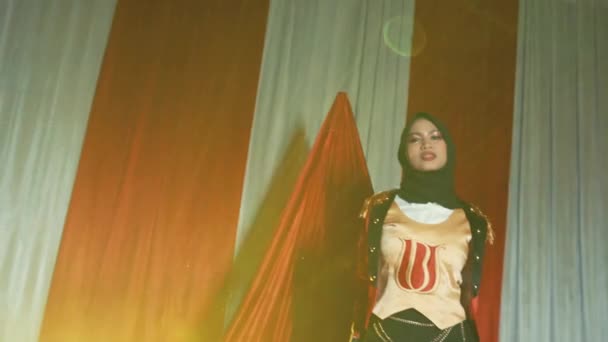 夜の背景にカーテンで赤いカーペットにポーズヒジャブのエレガントな女性 — ストック動画