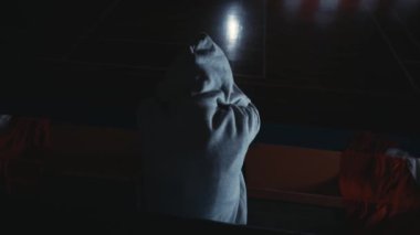 Karamsar bir insan silueti loş ışık altında, gece boyunca gizemli ve dramatik bir atmosfer yaratır.