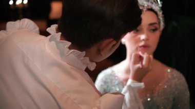 Parlak elbisesi ve tacı olan genç bir bayana ruj sürüp gece bir etkinliğe hazırlanıyor.