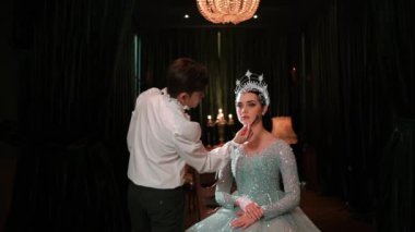 Parlak elbiseli zarif bir kadın ve gece boyunca bir kutlama etkinliğinde taçla pasta yiyor.