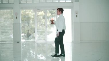 Beyaz fırfırlı gömlekli ve siyah pantolonlu bir adamın geniş, aydınlık bir odada elinde mumla yürüdüğü geniş profilli bir fotoğraf. Büyük mimari yalnız yolculuğunu vurguluyor..