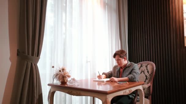 Homem Escrevendo Caderno Uma Mesa Escritório Casa Com Cortinas Luz — Vídeo de Stock