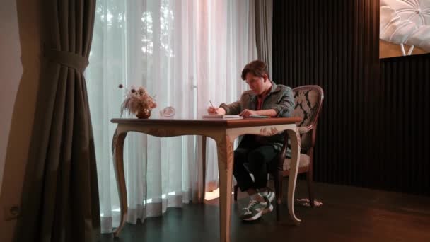 Homem Escrevendo Caderno Casa Com Pequeno Cão Assistindo Luz Natural — Vídeo de Stock