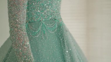 Yeşil dantelli bir elbise giymiş, geçmişi bulanık, gün ışığında zarafet ve moda detaylarına odaklanmış bir kadının yakın çekimi.