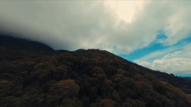 Gün ışığında dağların tepesindeki bulutlarla dramatik bir manzara.