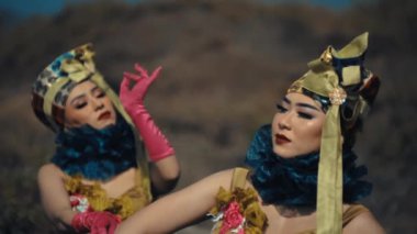 Endonezyalı bir kadın dansçının pembe eldivenlerle zarif el hareketleri yaparken detaylı bir yakın çekimi. Makyajına ve altın başlığına odaklanmış..