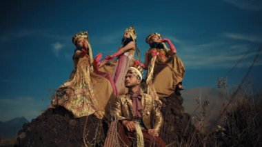 Canlı kostümlü geleneksel dansçılar alacakaranlıkta dramatik bir dağ zeminine karşı gösteri yapıyorlar..