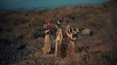 Cava kraliyet ailesi gibi giyinmiş dört kültür sanatçısından oluşan bir grup uzak bir şehir manzarasına bakan kuru bir tepede etkileşim ve sohbet içindeler..