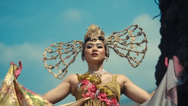 Kvinna Traditionell Kostym Med Utsmyckad Huvudbonad Och Vingar Mot Blå — Stockvideo