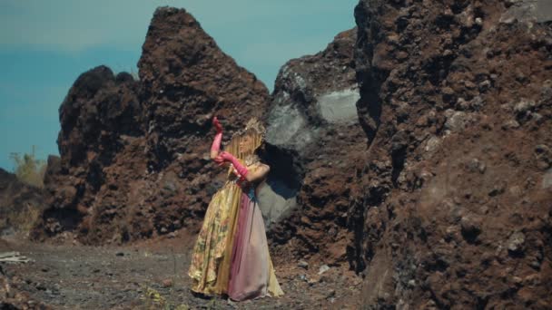 穿着华丽衣服的女人站在岩石间 在白天唤起了一种冒险和探索的感觉 — 图库视频影像