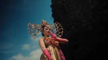 Geleneksel Balili dansçı kostümlü açık havada gün ışığında dramatik bir gökyüzü arka planıyla gösteri yapıyor.